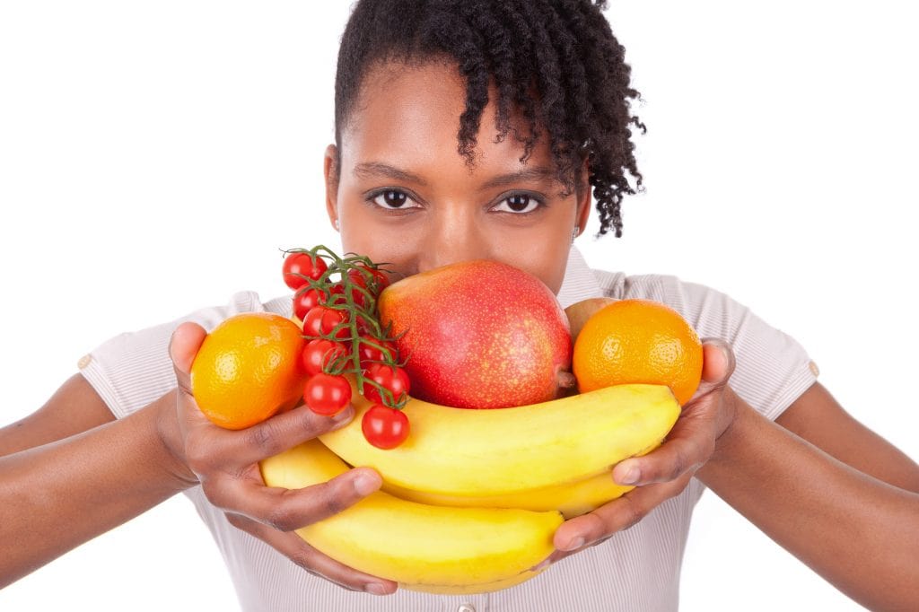 Uma mulher com várias frutas na frente da boca